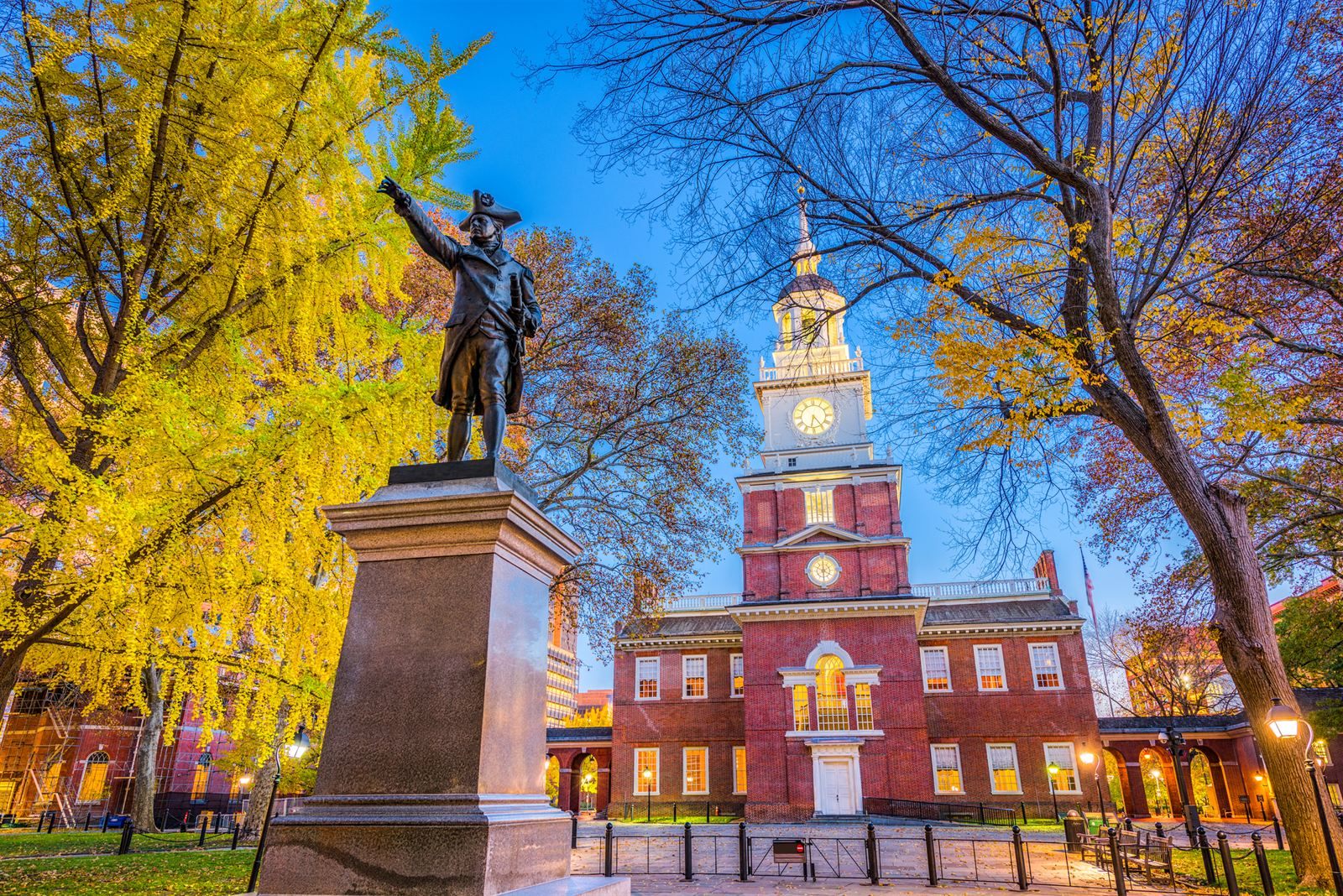 Independence Hall's clock tower behind a statue in fall color, a first stop among the places to visit in Pennsylvania and in any Pennsylvania travel guide