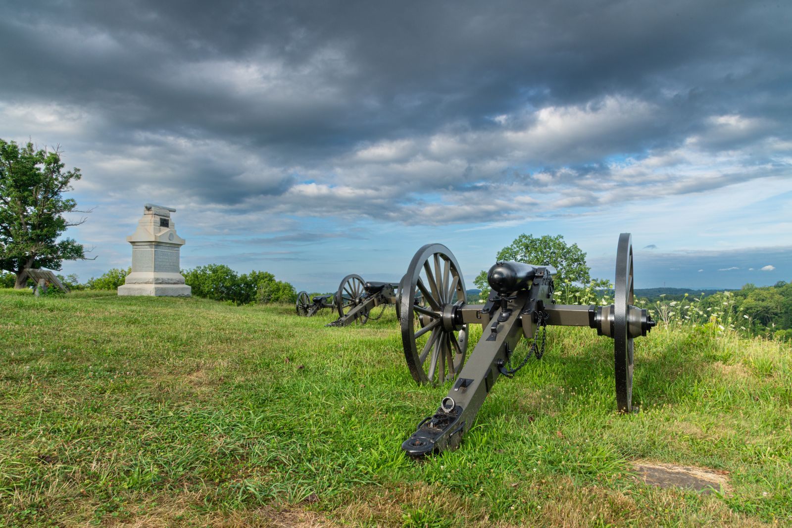 Civil War cannons and a monument on the Gettysburg battlefield under storm clouds, one of the top things to do in Pennsylvania